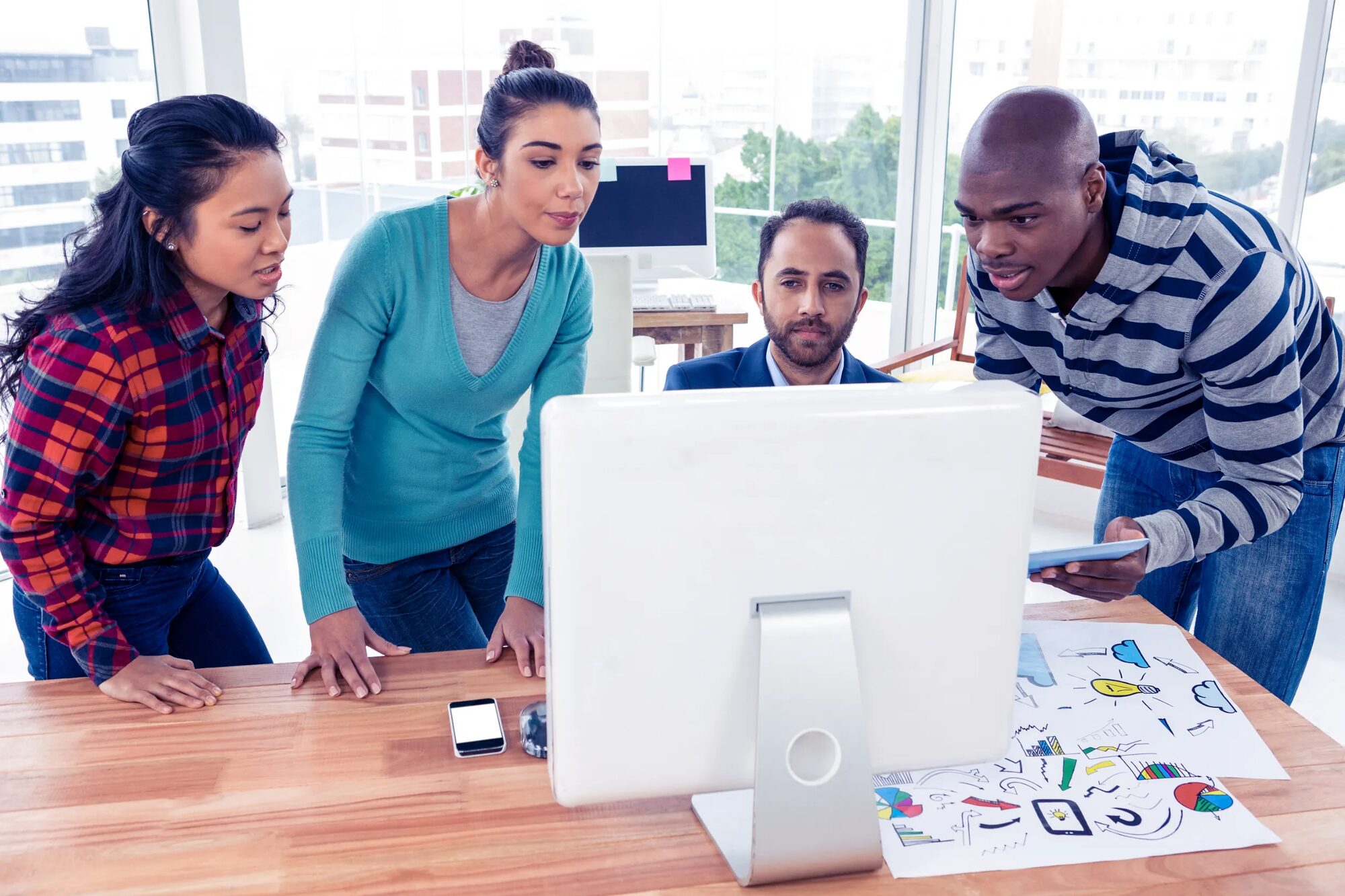 Insurance professionals collaborating around a desktop computer in a bright office